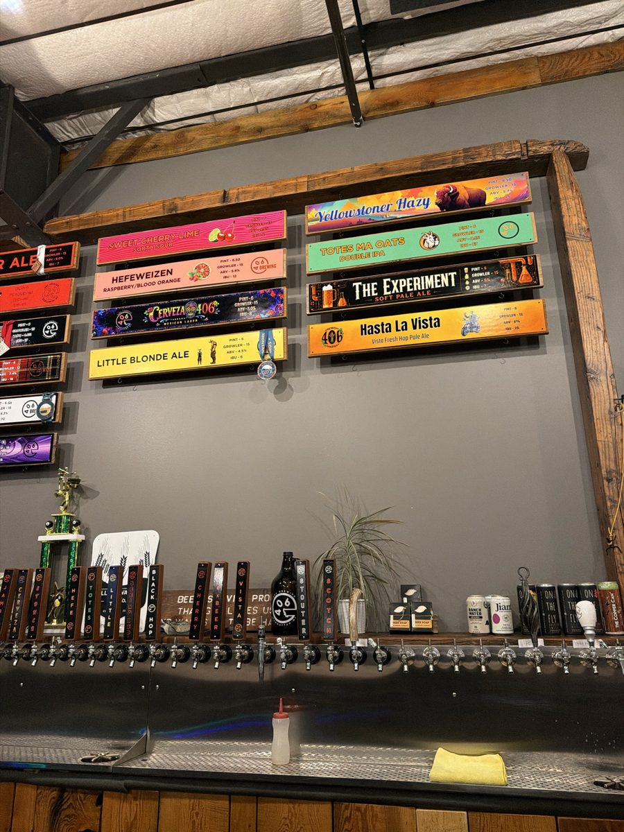 The 406 Brewing tap wall: colorful hand-painted beer signs on a slate grey wall framed in reclaimed wood